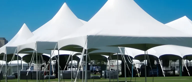 Multiple white tents set up on a grass turf.